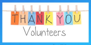 Letters on multiple colors hanging on a clothes line saying thank you with volunteers under on a white background.