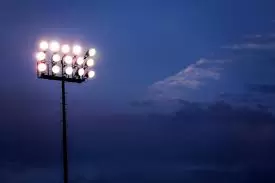 Stadium lights illuminated against a dark blue evening sky